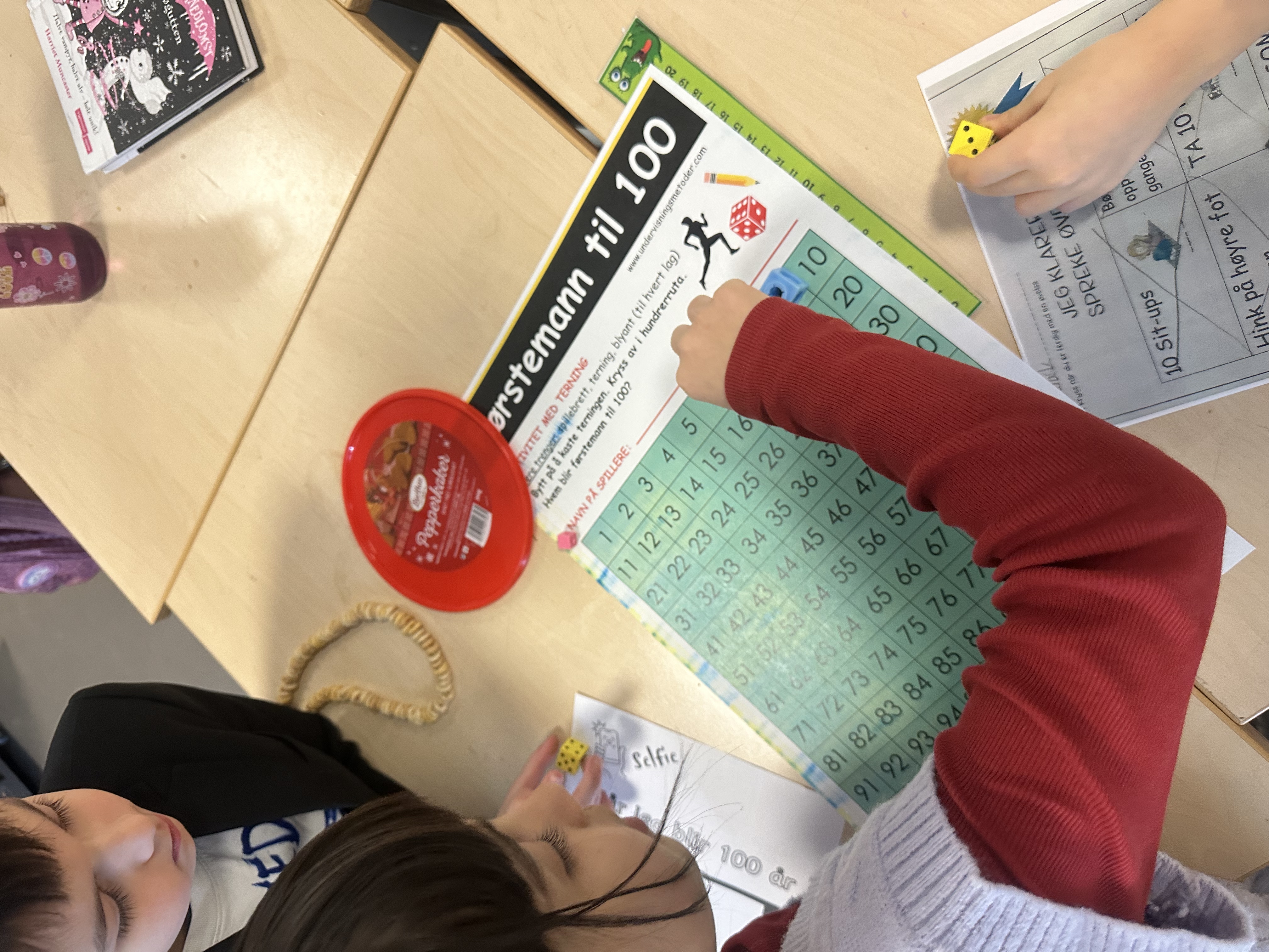 En gruppe mennesker som sitter ved et bord med bøker og en rød sirkel