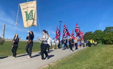Øvetoget med Majrostuen skoles fane i front med Monolitten i bakgrunnen