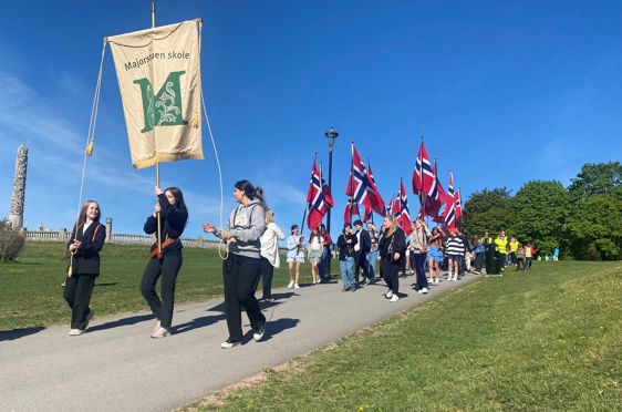 Øvetoget med Majrostuen skoles fane i front med Monolitten i bakgrunnen