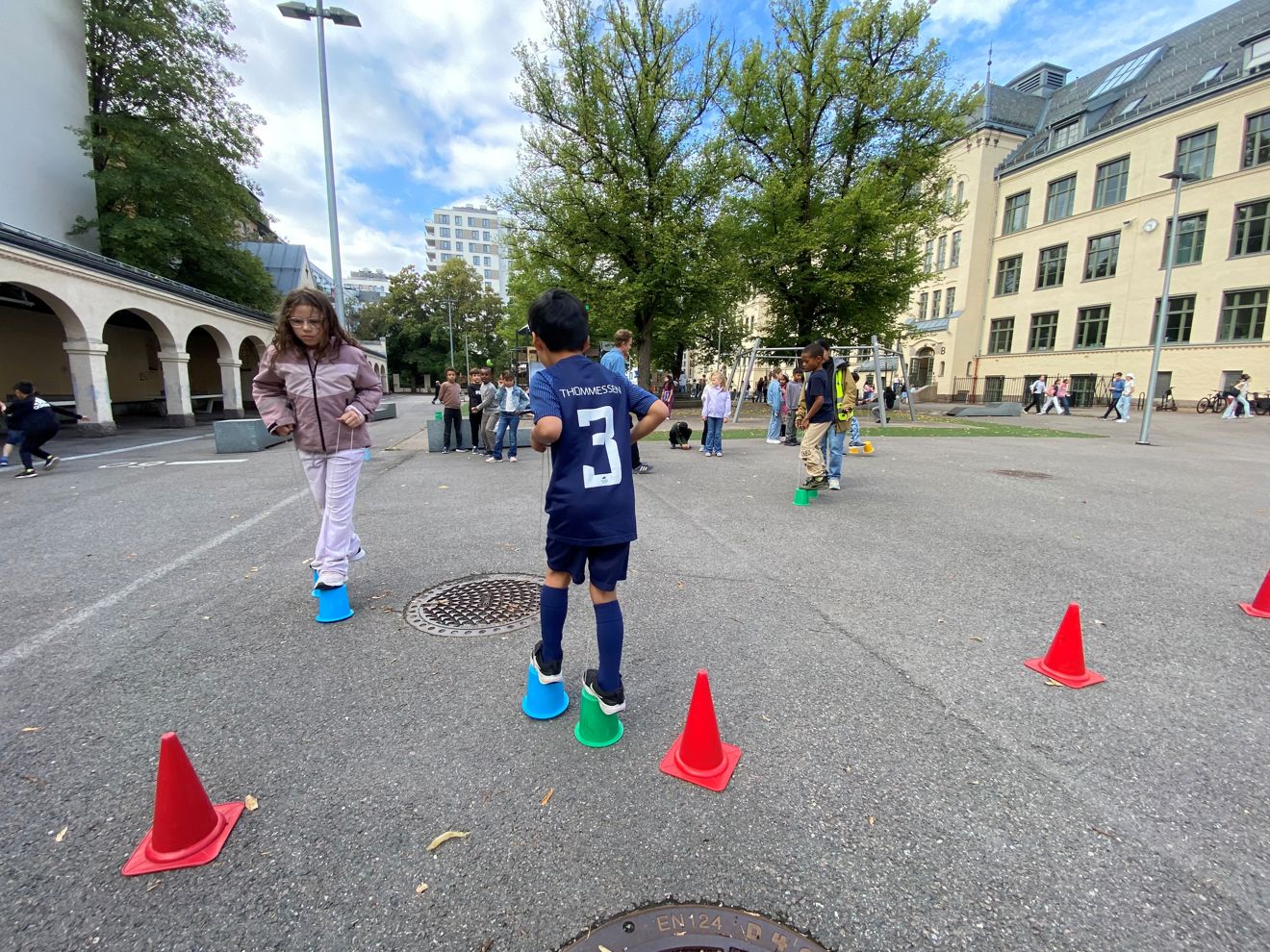 et barn som sto på en parkeringsplass med kjegler rundt seg et barn som sto på en parkeringsplass med kjegler rundt seg