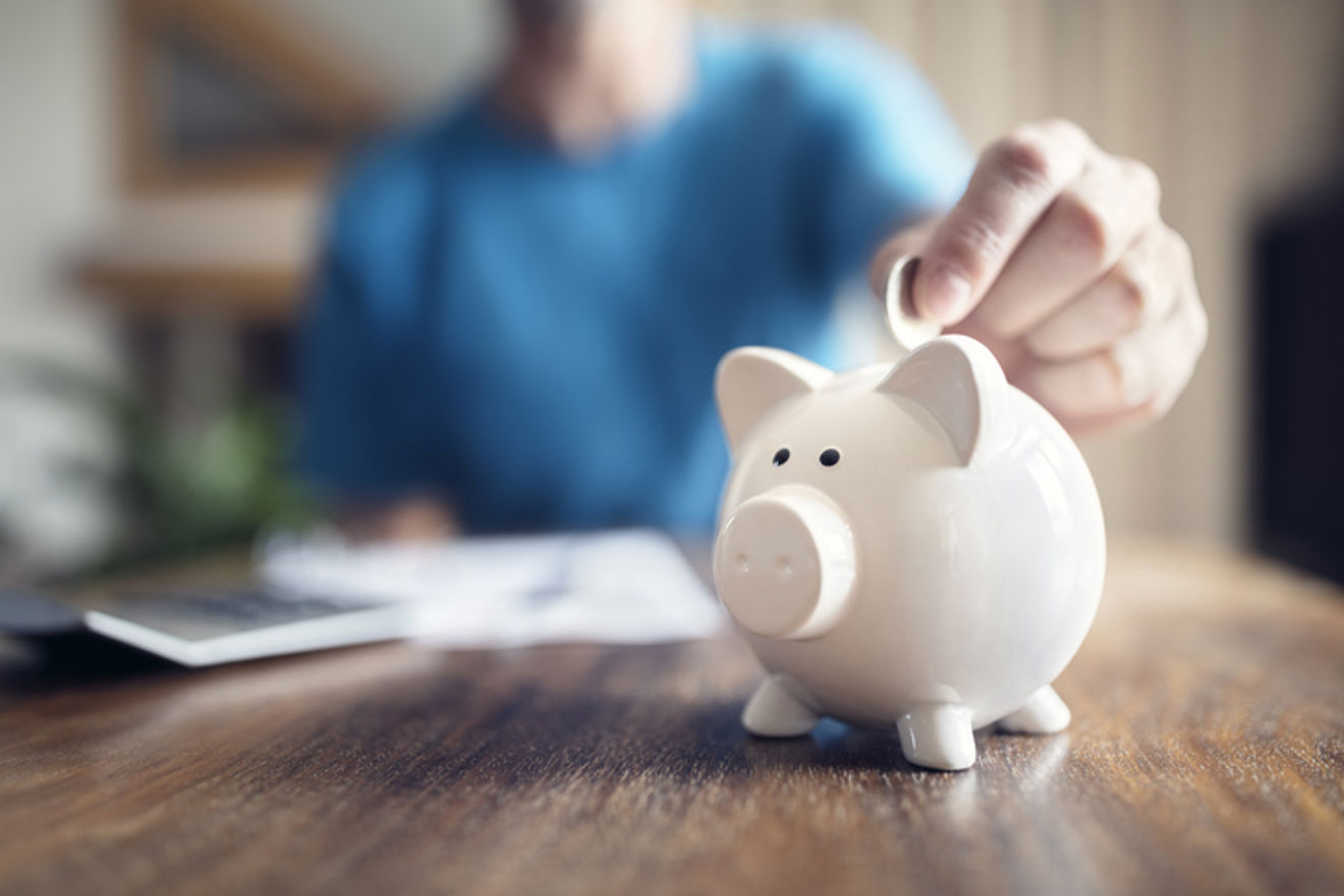 Foto: Brian A. Jackson / iStock en hånd som berører en liten hvit sparegris.