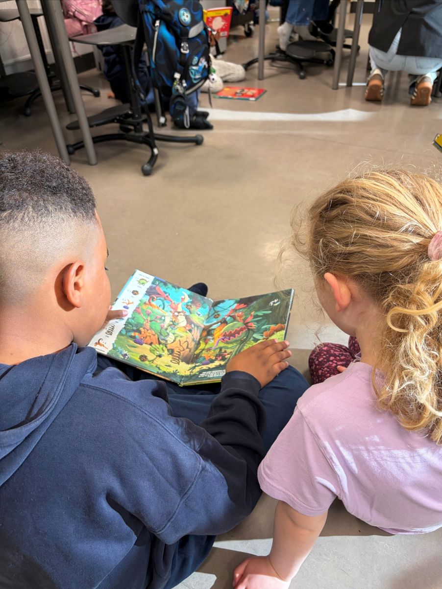 En person og et barn som sitter på gulvet og ser på en bok